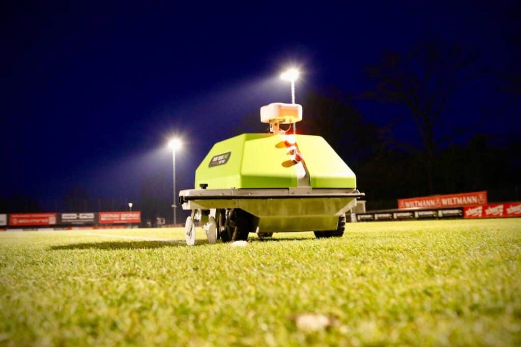 Autonomer Markierroboter markiert einen Sportplatz bei Flutlicht und sorgt auch bei Dunkelheit für präzise Linienmarkierungen.